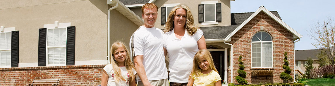 Family with two daughters standing in front of their home